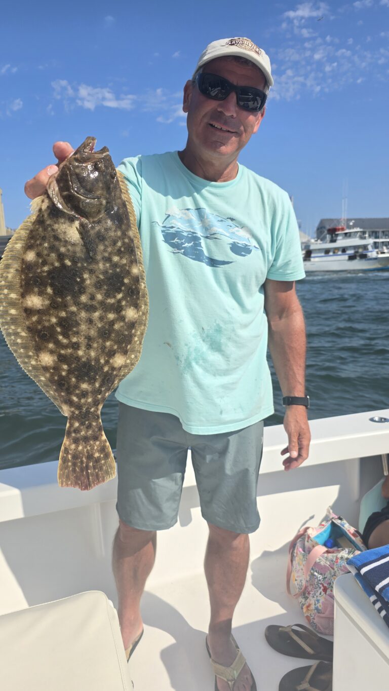Smiling angler holding large flounder caught on Saltwater Adventures fishing charter in Ocean City Maryland