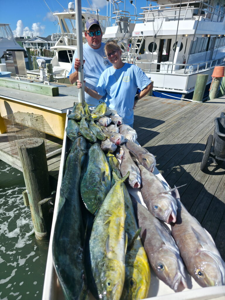 Couple displaying large catch of mahi-mahi and golden tilefish on cleaning table after Ocean City Maryland offshore charter