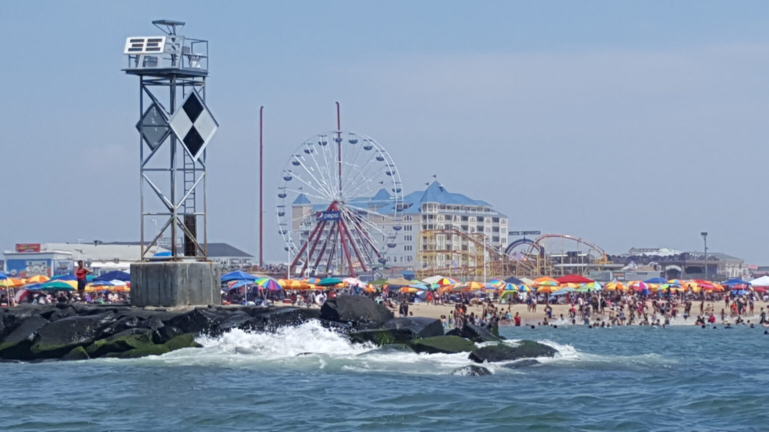 Ocean City Maryland inlet jetty with boardwalk ferris wheel and beach in background during summer season