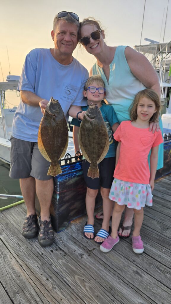 Family of four with flounder at sunset after Ocean City Maryland bay fishing charter