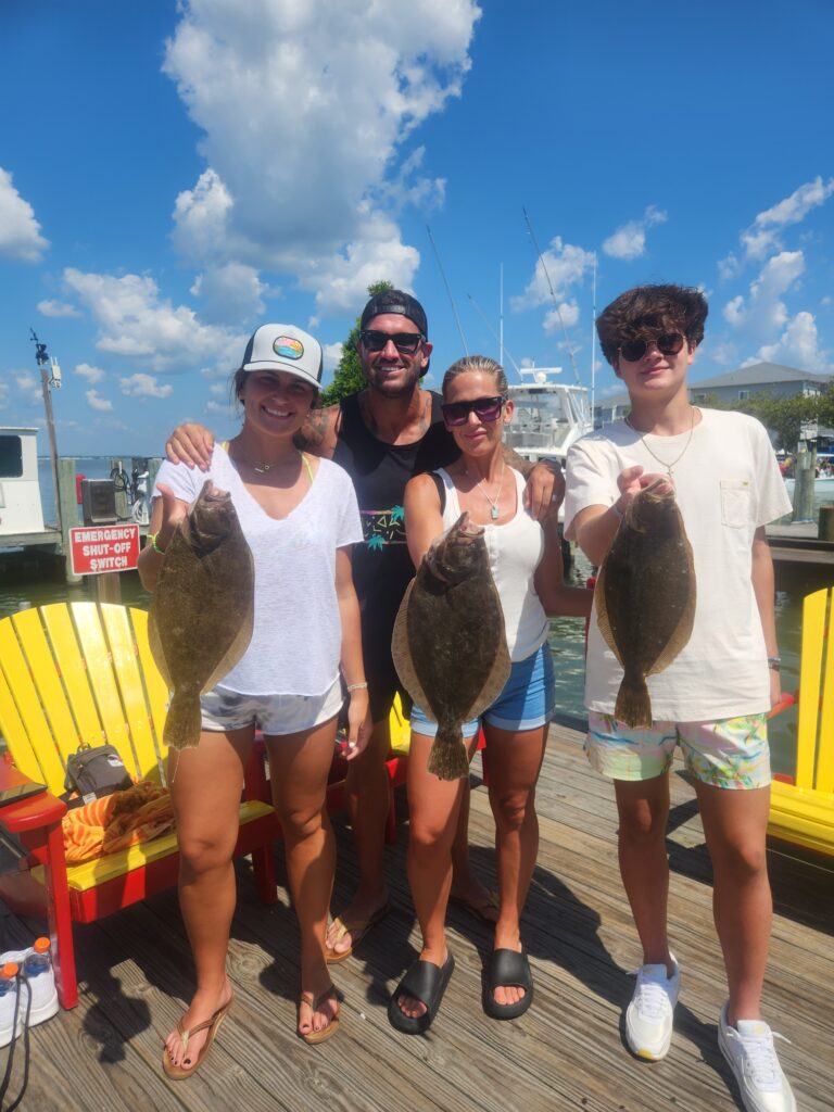 Family of four holding flounder at Ocean City marina after successful bay fishing charter