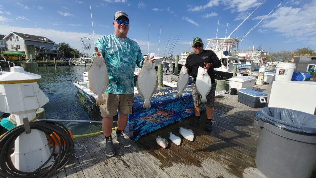 Two anglers holding limit of flounder at Ocean City marina after successful bay fishing charter